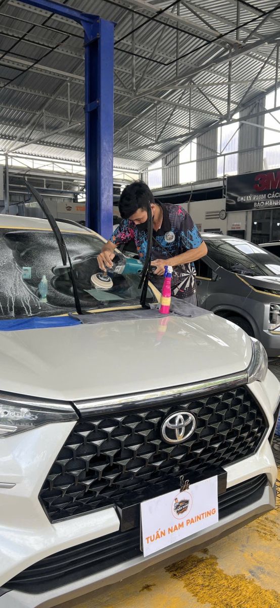 Kỹ thuật viên đang đánh bóng kính lái xe ô tô